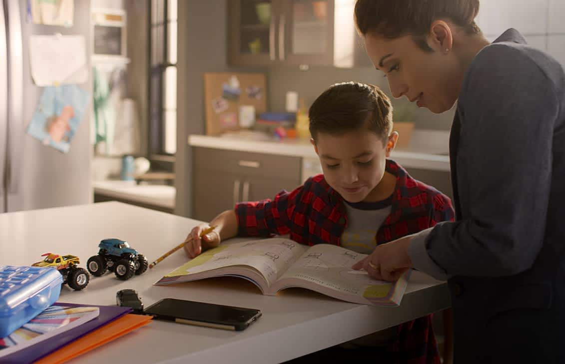 Woman helping a child with homework at a kitchen island