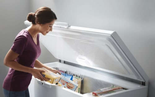 Person taking food out of an open chest freezer