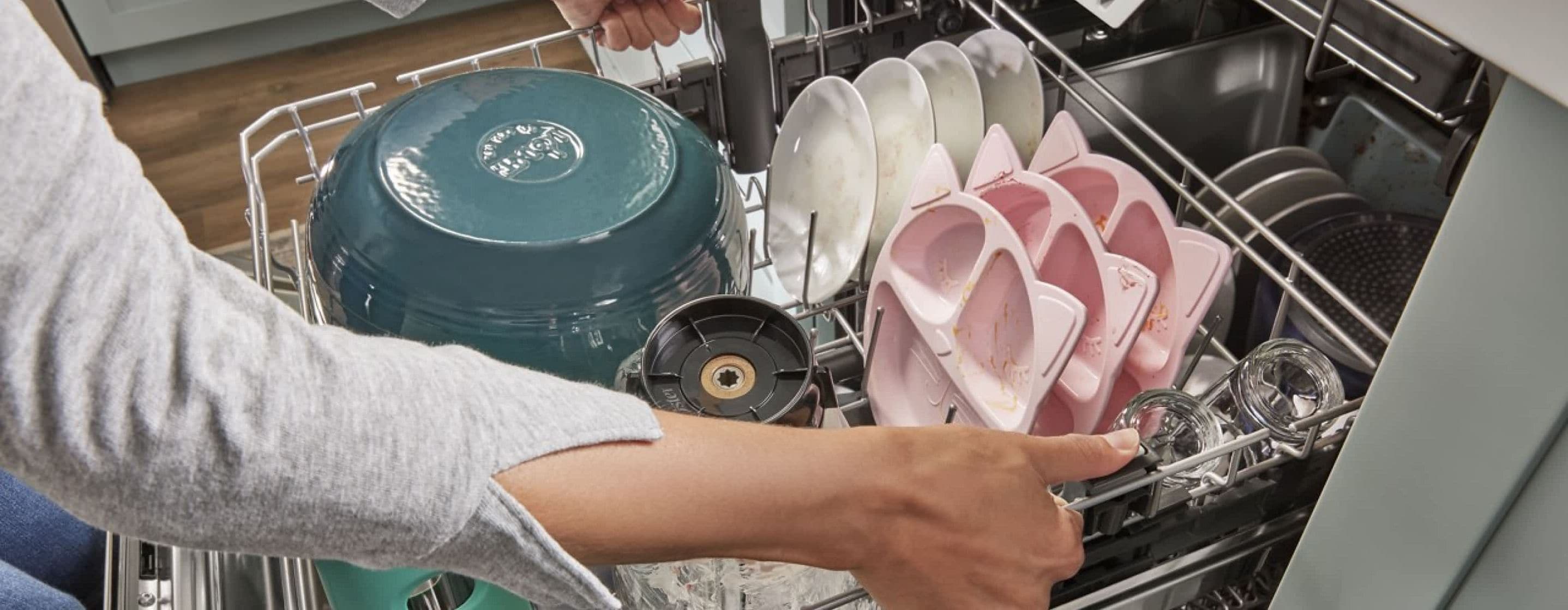 A person lowering a fully loaded Adjustable 2nd Rack in a Whirlpool® 3rd Rack Dishwasher