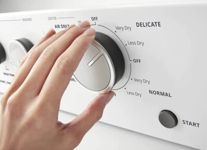 A hand turns a knob on a Whirlpool® Stacked Laundry Center