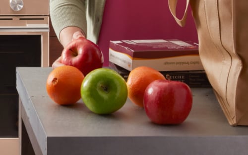 A person unloading apples on a counter