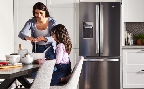  Woman and child cooking in front of a French door refrigerator