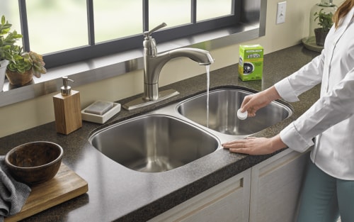 Person adding affresh® to a kitchen sink drain