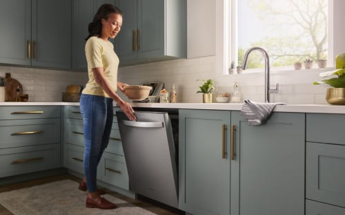 A person opening a Whirlpool® Dishwasher in a modern kitchen