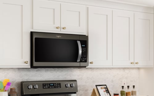 Whirlpool over-the-range microwave and oven set in a kitchen with neutral backsplash.