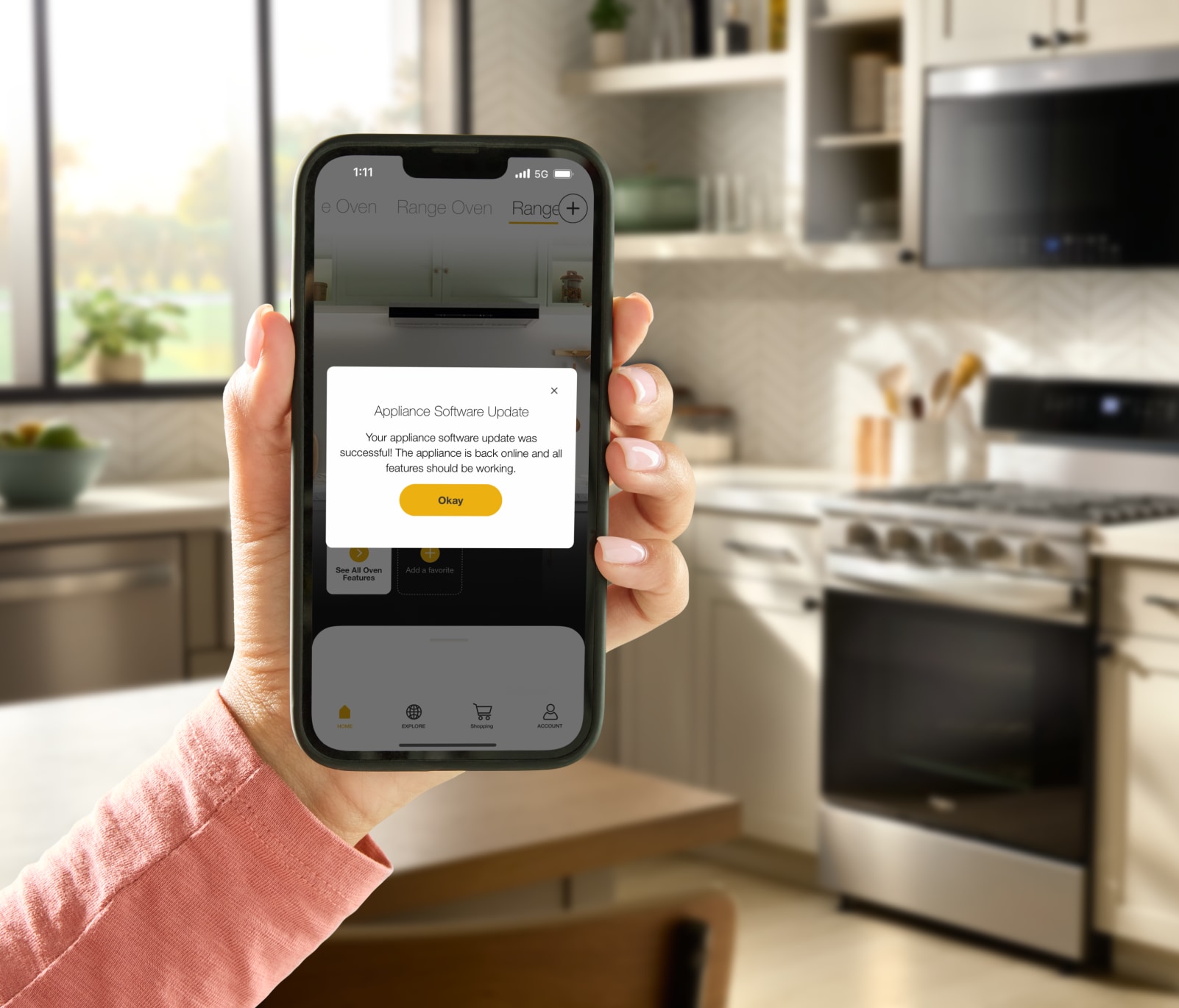 A hand holding the Whirlpool® App showing an update for the Whirlpool® Smart Range