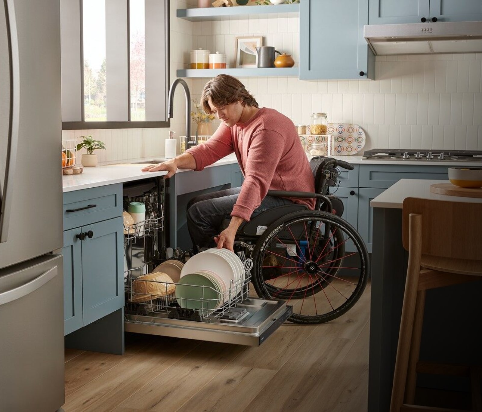 A person in a wheelchair unloading dishes from an ADA Compliant dishwasher