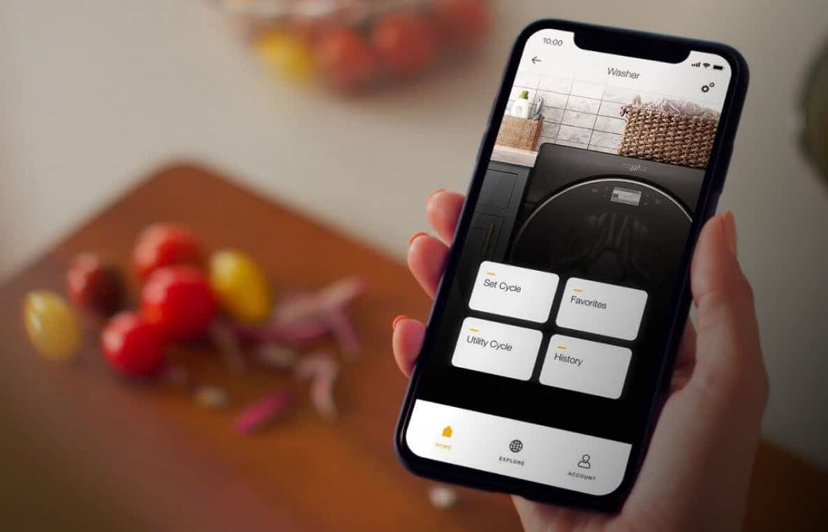 A hand holding a phone displaying the Whirlpool® App