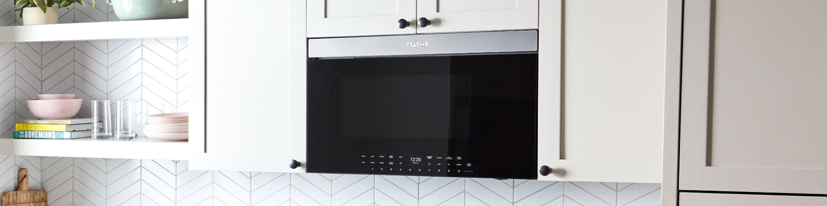 A Whirlpool® Low Profile Microwave in a sleek, white, modern kitchen