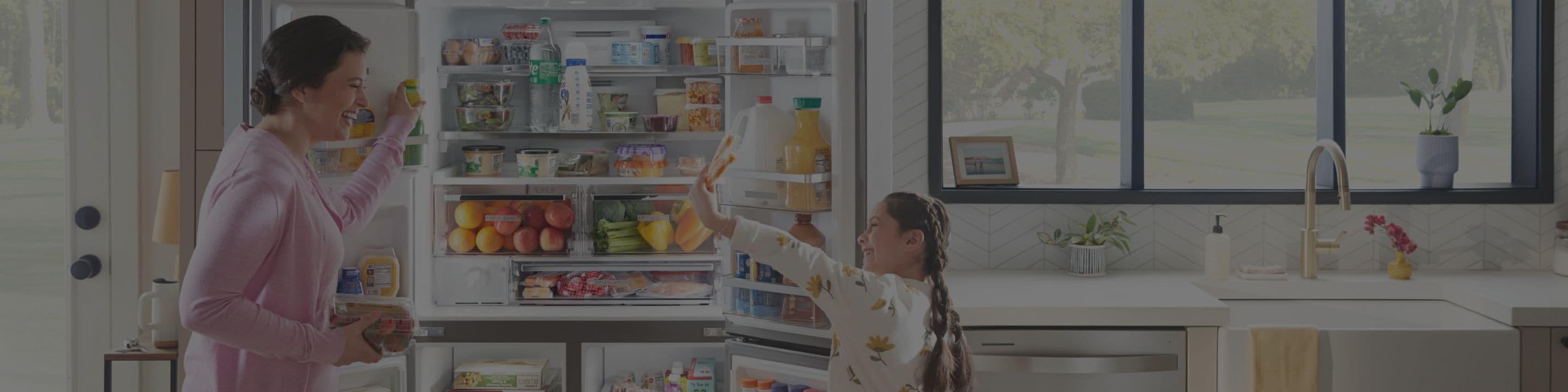 A mother and daughter standing in front of an open Whirlpool® refrigerator