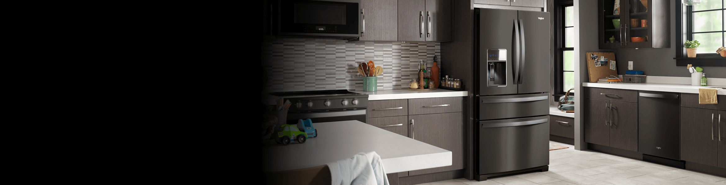 A black stainless steel refrigerator in a kitchen with other appliances.