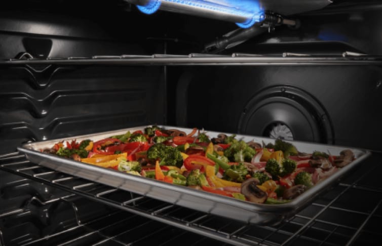 A sheet pan with vegetables inside an oven