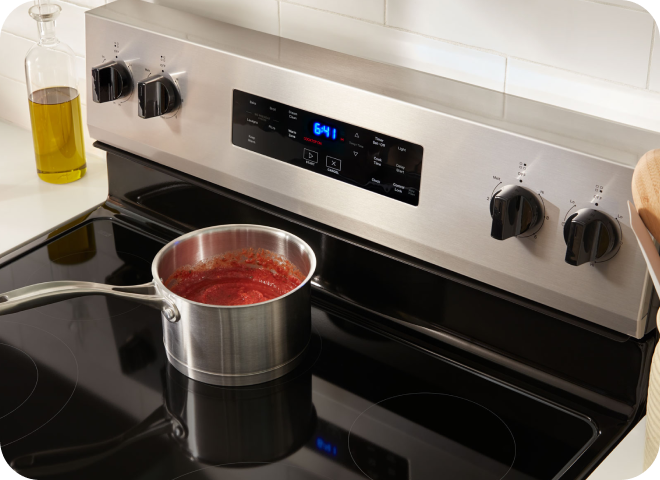 A pot a pasta sauce simmering on a stovetop.