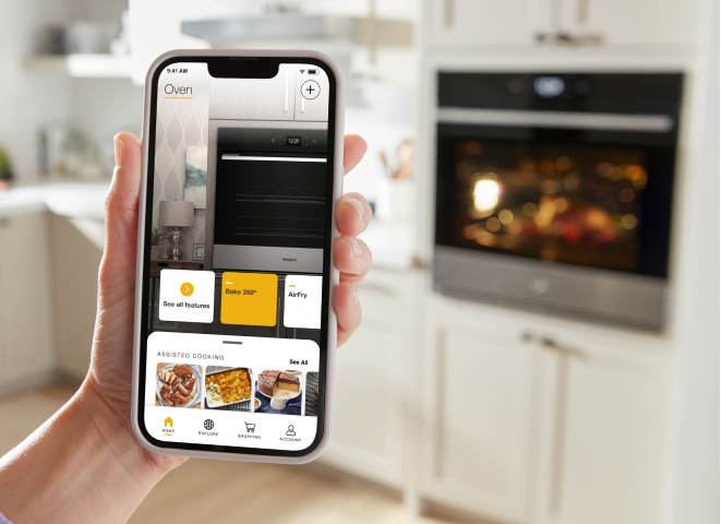 A hand holding a phone displaying the Whirlpool® App